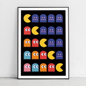 Op de afbeelding: Een ingelijste print met een retro videogame-ontwerp. Het kunstwerk toont een herhalend patroon van gele Pac-Man-personages en kleurrijke geesten in rood, oranje, blauw en roze tegen een zwarte achtergrond. De print zit in een zwart frame.