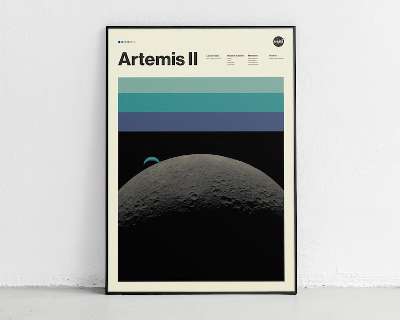 May include: Framed poster featuring the Artemis II mission. The design includes a depiction of the moon's surface, a crescent-shaped planet, and horizontal bands of teal and blue. The NASA logo is visible in the upper right corner.
