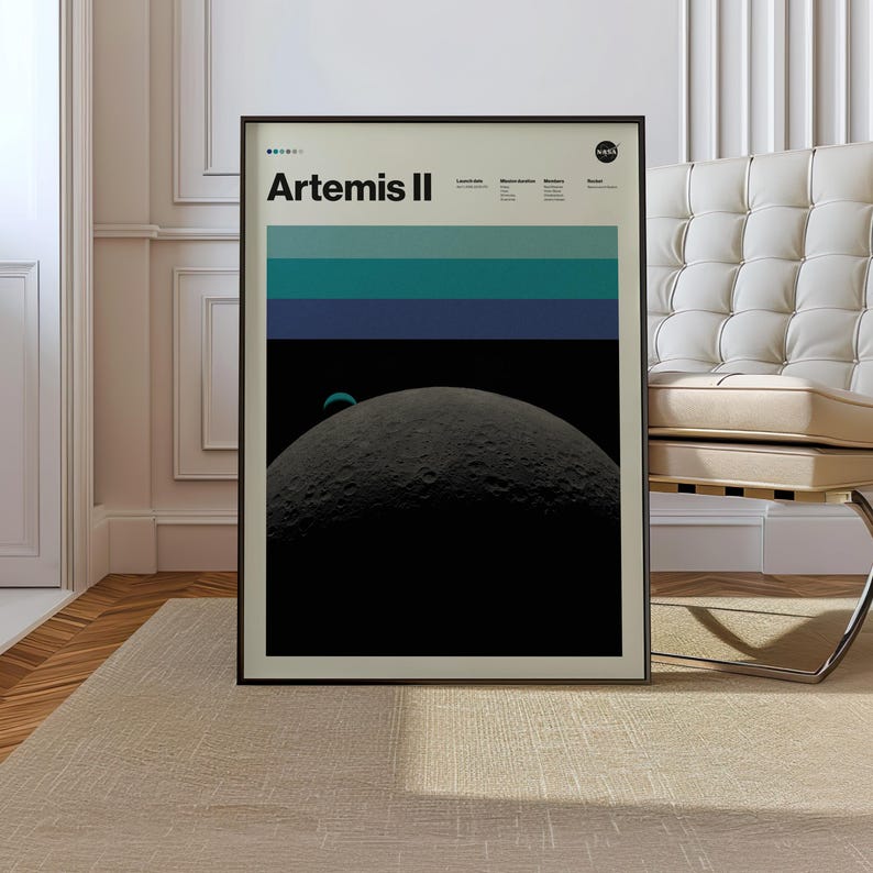 May include: A framed poster with the text "Artemis II" in white against a black background. The poster features a graphic of the moon and a series of horizontal blue and teal stripes. The NASA logo is in the upper right corner.