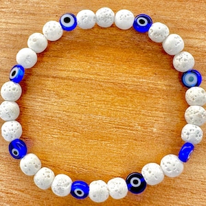 May include: White lava rock beaded bracelet with blue evil eye charms.
