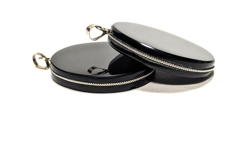 May include: Two black round pendants with silver trim. The pendants are smooth and shiny.
