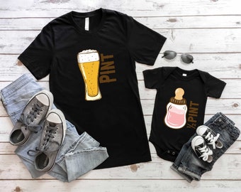 May include: Two black t-shirts with a beer glass and a baby bottle graphic. The beer glass says "Pint" and the baby bottle says "1/2 Pint".