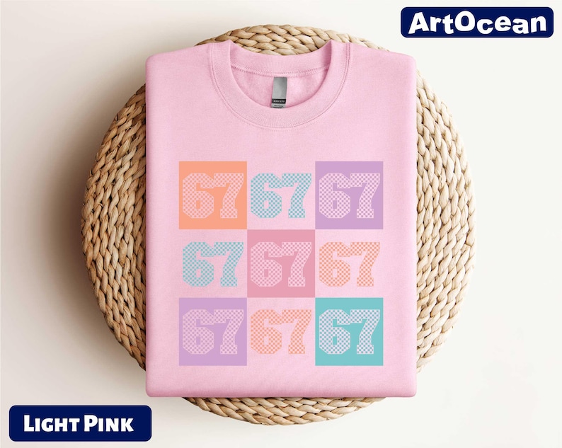 A pink t-shirt with the numbers '67676767' printed on it, displayed on a woven basket.