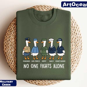 May include: Military green sweatshirt featuring cartoon ducks dressed in military uniforms representing the Marines, Air Force, Army, Navy, and Coast Guard. The text "NO ONE FIGHTS ALONE" is printed below the ducks.