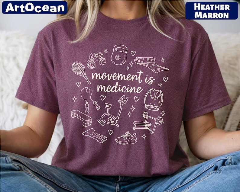 A person wearing a purple t-shirt with a graphic design featuring various fitness-related items and the text "motion is medicine".