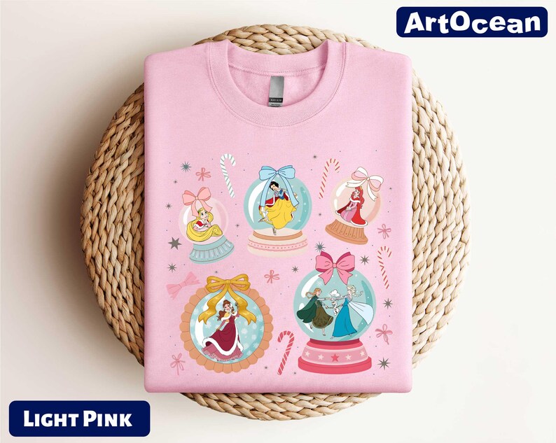 A pink t-shirt with a design featuring various cartoon characters and snow globes.