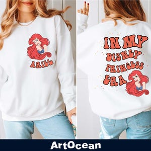 a woman wearing a white sweatshirt with the words i am disney princess on it