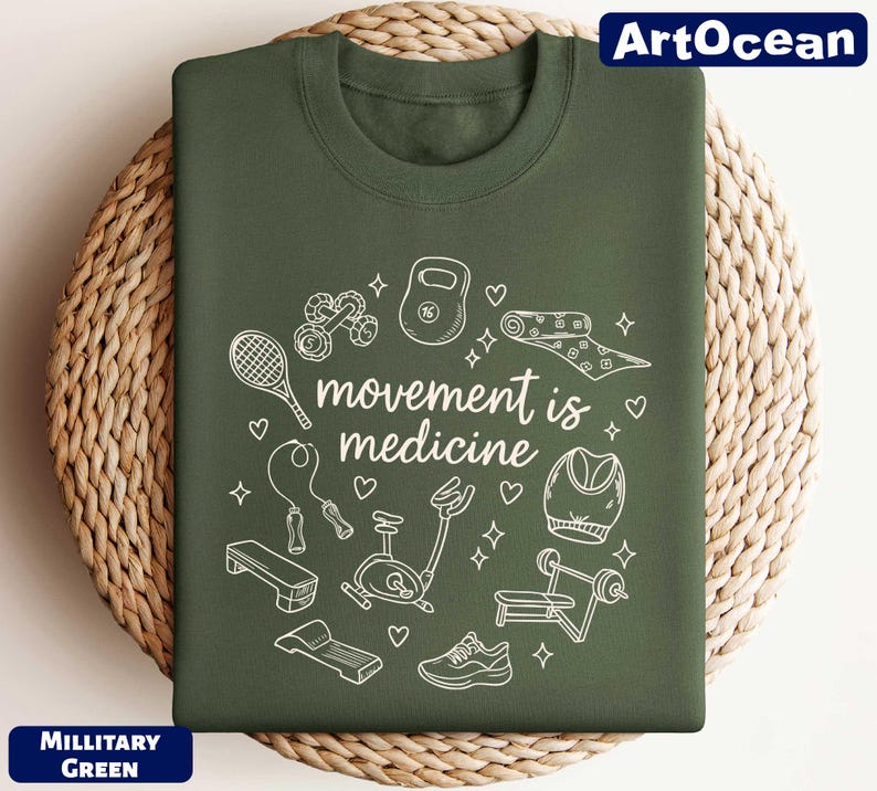 A green t-shirt with a white graphic design featuring various fitness-related objects such as a tennis racket, dumbbells, and a yoga mat, along with the text "motion is medicine".