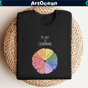 a black t - shirt with the words play and learning on it