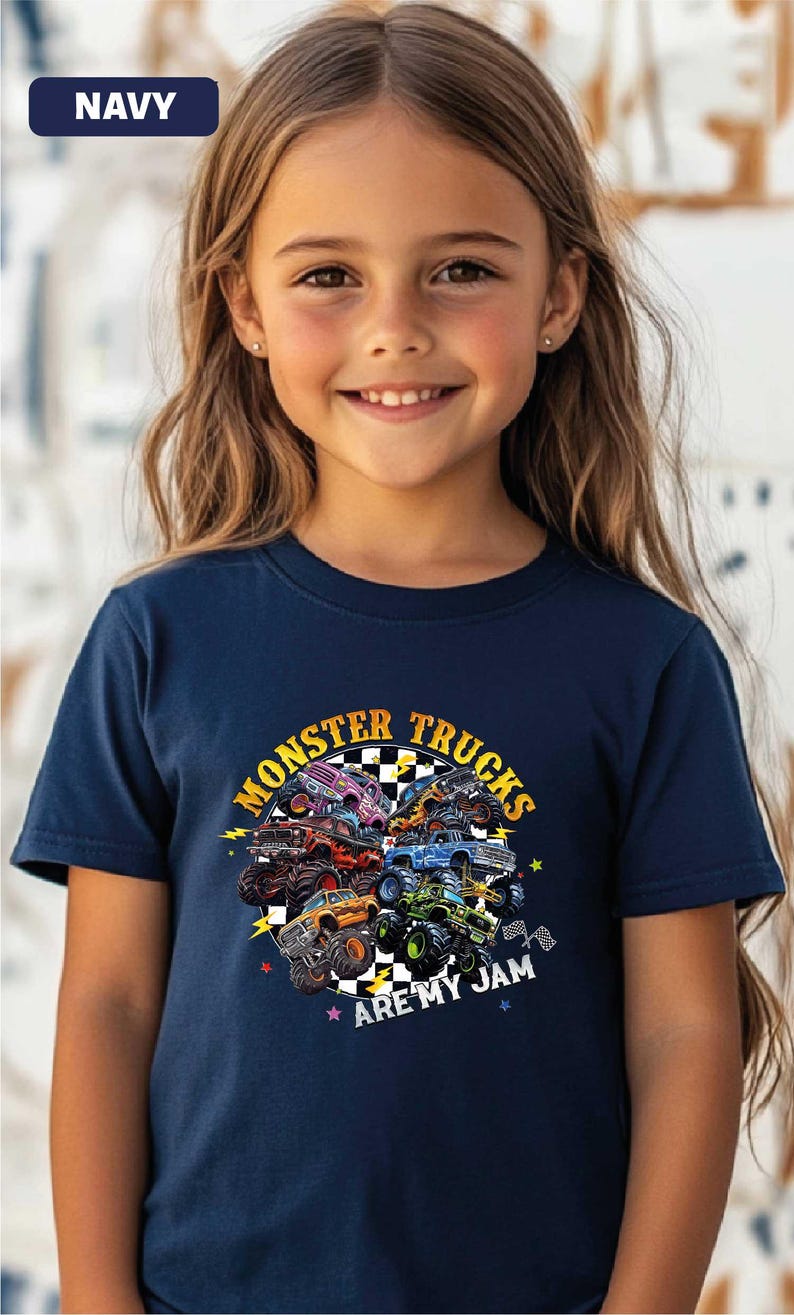 A young girl wearing a navy blue t-shirt with a graphic design of monster trucks and the text "MONSTER TRUCKS ARE MY JAM".