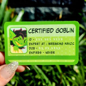 May include: A green and white Certified Goblin ID card. The card features a cartoon goblin illustration and the text "CERTIFIED GOBLIN". The card's details include "EXPERT AT: WREAKING HAVOC" and "EXPIRES - NEVER".