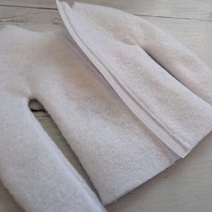 May include: White fleece fabric with a zipper sewn along the center seam. The fabric is folded in half, showing the inside of the fabric.