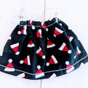 May include: A black skirt with a white and red Santa hat pattern. The skirt has an elastic waistband and is made of a soft, comfortable fabric.