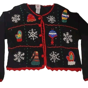 Puede incluir: Cárdigan de punto negro con ribete rojo y diseños navideños bordados, incluyendo copos de nieve, guantes y gorros.