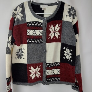 May include: A cream, red, black, and gray cardigan with a snowflake pattern. The cardigan has a button closure and long sleeves.