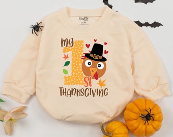 May include: A cream-colored long-sleeved onesie with the text "My 1st Thanksgiving" and a cartoon turkey wearing a pilgrim hat.