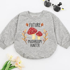 Puede incluir: Una sudadera gris de manga larga con un gr&aacute;fico de hongo y el texto "FUTURE MUSHROOM HUNTER".