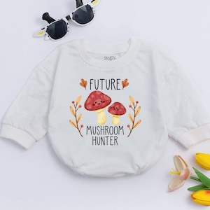 Puede incluir: Mono blanco de manga larga para beb&eacute; con un gr&aacute;fico de dos setas de dibujos animados y el texto "FUTURE MUSHROOM HUNTER".