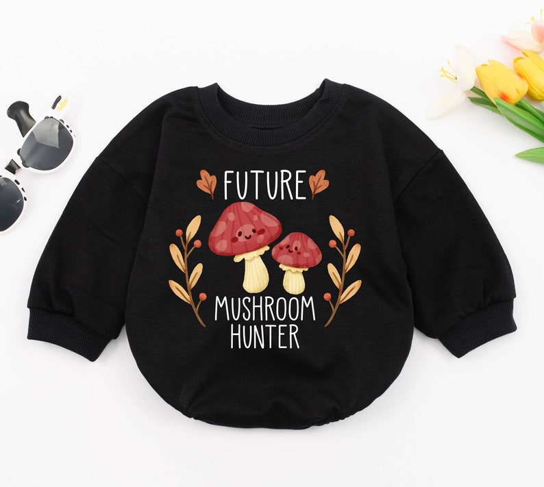 Puede incluir: Sudadera negra de manga larga con un gr&aacute;fico blanco de dos setas y el texto "FUTURE MUSHROOM HUNTER".