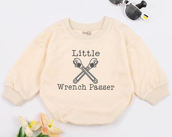 May include: A light beige long-sleeved baby onesie with the text "Little Wrench Passer" and a graphic of two wrenches crossed over each other.