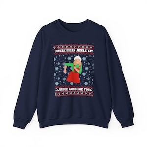 May include: A navy blue sweatshirt with a Christmas-themed design. The graphic shows a person in a green top and red skirt, with the text "JINGLE BELLS JINGLE YAY" and "JINGLE GOOD FOR YOU". Snowflakes and patterns add to the festive look.
