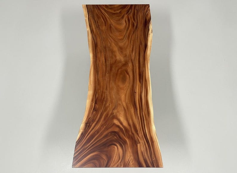 Puede incluir: Una losa de madera rectangular con borde vivo y forma natural y org&aacute;nica. La veta de la madera presenta un color marr&oacute;n c&aacute;lido y rico con patrones arremolinados m&aacute;s oscuros. Ideal para una mesa o encimera.