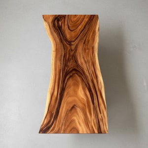 Puede incluir: Una losa de madera rectangular con borde vivo, de forma natural y org&aacute;nica. La madera presenta un color marr&oacute;n c&aacute;lido y rico con vetas oscuras y arremolinadas. La losa es probablemente una pieza decorativa o funcional, como un estante o una mesa.
