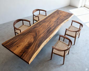 Pode incluir: Uma grande mesa de jantar de madeira maciça com borda natural, rodeada por quatro cadeiras. Os tons castanhos ricos e os padrões de grão únicos da mesa são complementados pelos assentos tecidos claros e pelas estruturas de madeira curvas das cadeiras. Comprimento da mesa aprox. 240 cm.