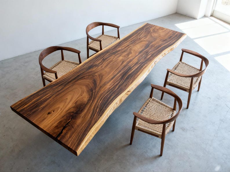 Puede incluir: Una mesa de comedor grande de madera maciza con borde natural, rodeada de cuatro sillas. Los tonos marrones ricos y los patrones de vetas &uacute;nicos de la mesa se complementan con los asientos tejidos claros y los marcos de madera curvados de las sillas. Largo de la mesa aprox. 240 cm.