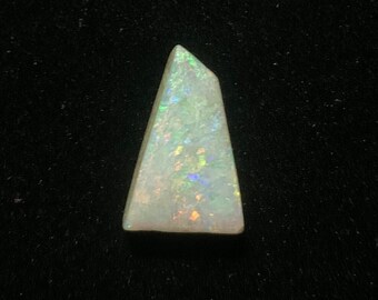 May include: A white opal gemstone with iridescent flashes of color, cut into a triangular shape.