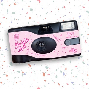May include: Pink disposable camera with black accents and a white flash. The camera is decorated with a pink and white design that includes a disco ball, a cocktail glass, a bottle of champagne, a pair of sunglasses, and a hat. The text "Rachel's Hens" and "25 June 2024" are printed on the camera. The text "Turn on Flash" is printed on the camera with a pink arrow pointing to the right.