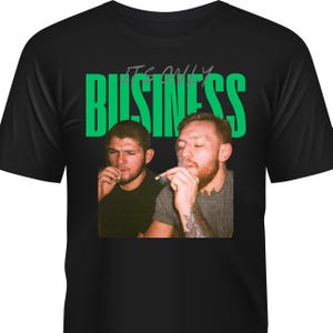 May include: Black t-shirt featuring a graphic of two men smoking, with the words "IT'S ONLY BUSINESS" in green block letters above them. The image has a vintage, slightly faded look.