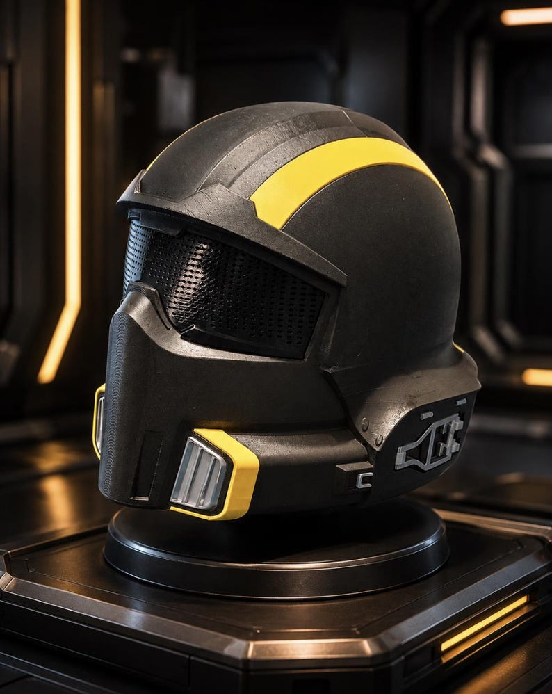 May include: A matte black helmet featuring a prominent yellow stripe running across the top and yellow accents near the chin guard. The helmet includes a dark, textured mesh visor and mechanical-looking side details with silver-toned hardware.