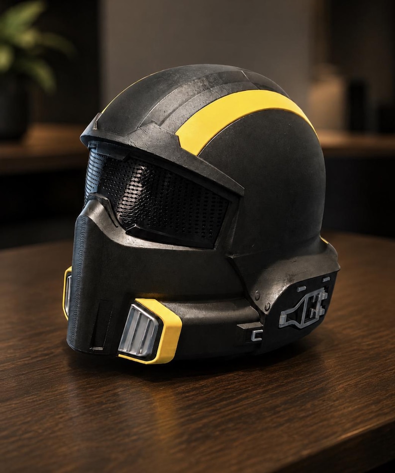 May include: A matte black full-face helmet featuring a prominent yellow stripe running across the top, a dark mesh visor, and yellow-accented vents on the lower front section. The side of the helmet displays a silver mechanical detail.