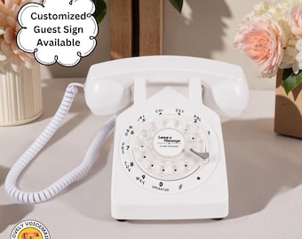 May include: A white rotary dial telephone with a coiled handset cord. The phone has a circular dial with numbers and letters. The text "Leave a Message" is visible on the dial. The image also includes the text "Customized Guest Sign Available".