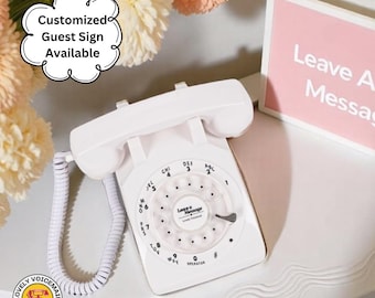 May include: A white retro rotary phone with a coiled handset cord. The phone has a circular dial with numbers and letters. Text on the phone reads "Leave A Message". A sign that says "Leave A Message" is in the background. The image also includes text that says "Customized Guest Sign Available".