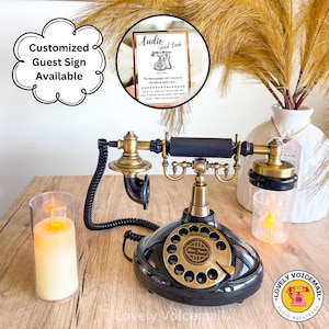 Pu&ograve; includere: Un telefono vintage nero e ottone con quadrante rotante, con un cavo nero, una candela e un cartello con la scritta "Audio Guest Book". Il cartello &egrave; in una cornice dorata. Il telefono ha un'etichetta "Retro Phone" sul quadrante.