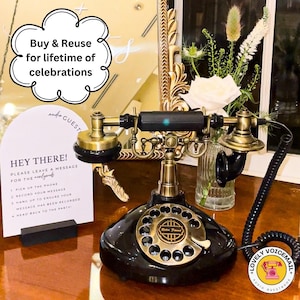 Pu&ograve; includere: Un telefono vintage nero e ottone con quadrante rotante e cavo a spirale. Il telefono &egrave; su una superficie di legno. Un cartello dice: "Hey There! Per favore, lascia un messaggio per gli sposi."