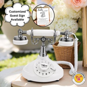 May include: A white vintage telephone with silver detailing and a rotary dial. The phone features a white handset and a coiled cord. A sign reading "Audio Guest Book" is visible. The phone is labelled "Leave a Message".