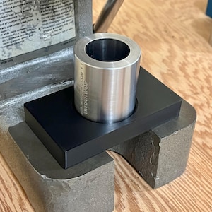 Puede incluir: Un cilindro de metal plateado se encuentra en una base rectangular negra, que est&aacute; colocada sobre una m&aacute;quina de metal gris. El cilindro tiene un centro hueco. El texto "SWEDISH WRAP" es visible en el cilindro. La m&aacute;quina est&aacute; sobre una superficie de madera.