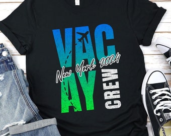 May include: Black t-shirt with a green and blue gradient design. The text "VACAY" is printed in white with a plane icon above the "A". The text "New York 2024" is printed in white below the "A". The text "CREW" is printed in white vertically on the right side of the shirt.