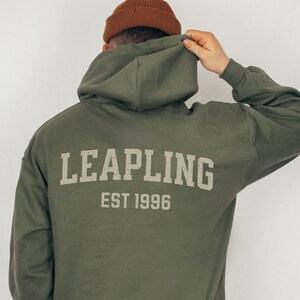 May include: A green hooded sweatshirt with the text "LEAPLING EST 1996" printed on the back.