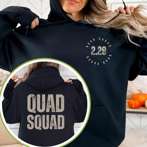 May include: Black hoodie with a distressed white graphic on the front that says "QUAD SQUAD 2.29" in a circle. The back of the hoodie has a distressed white graphic that says "QUAD SQUAD".