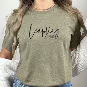 May include: A green t-shirt with the text "Leapling EST 2000" in black script font.