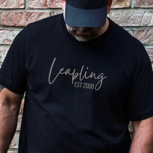 May include: A black t-shirt with the text "leapling EST 2000" in gray lettering.