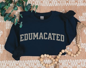 May include: A navy blue sweatshirt with the text "EDUMACATED" in a distressed, gray font.