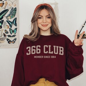 Op de afbeelding: Een bordeauxrood sweatshirt met de tekst "366 CLUB MEMBER SINCE 1984" in wit en grijs.