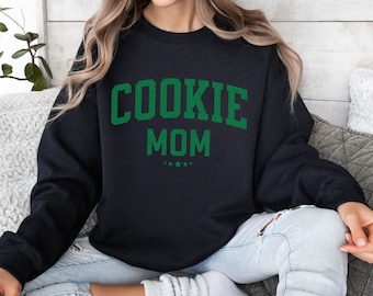 May include: Black sweatshirt with green text that reads "COOKIE MOM" with five stars underneath.