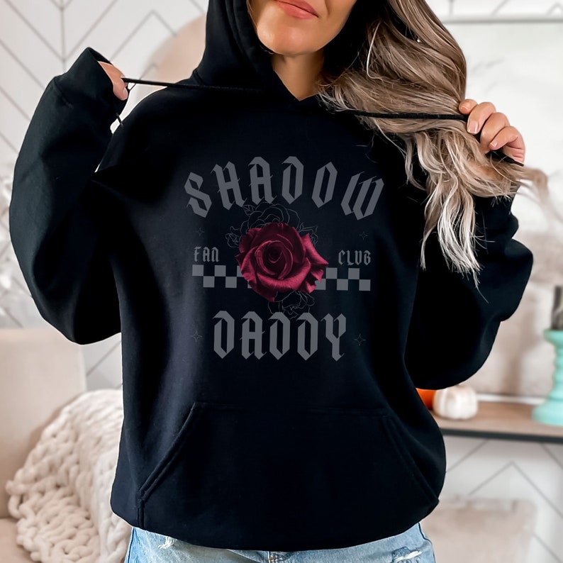 May include: Black hooded sweatshirt with the text "SHADOW DADDY" in a gothic font, a red rose, and the words "FAN CLUB" above the rose.