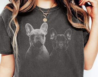 May include: A charcoal gray short-sleeve t-shirt featuring a graphic print of two French Bulldogs on the chest. The shirt has a crew neckline and a relaxed fit. The fabric has a washed, faded appearance. The word PEPPER is printed in the corner.